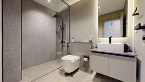 Une salle de bain moderne avec une douche à parois de verre, des toilettes blanches et un meuble-lavabo avec un miroir.