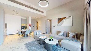 Un salon moderne avec un ensemble de canapés, une table à manger avec des chaises, et un coin cuisine à l’arrière-plan.