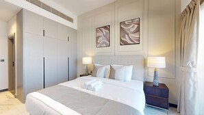 Une chambre d’hôtel avec un grand lit, deux tables de chevet avec des lampes, une armoire et des œuvres d’art abstraites accrochées au mur.