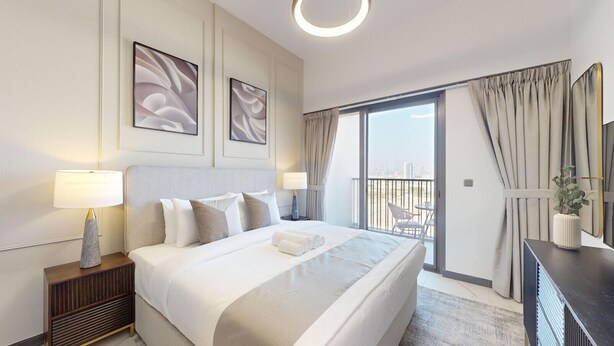 Une chambre d’hôtel moderne dotée d’un grand lit, d’une table de chevet, d’un bureau et d’un balcon avec des rideaux.