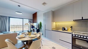 Une cuisine moderne dotée d’un îlot central, d’appareils électroménagers intégrés et offrant une vue sur l’extérieur.
