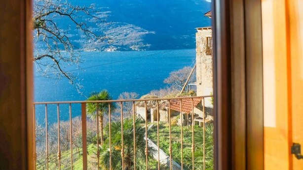 A view from a window overlooking a mountainous landscape with a body of water and a building with a red roof. - GRABBIA 1 by Deign Studio (Bellano)