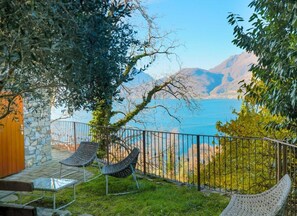A patio with two chairs and a table, overlooking a lake and mountains.