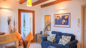 A cozy living room with a blue sofa, wooden beams, and framed artwork. - GRABBIA 1 by Deign Studio (Bellano)