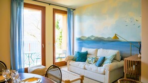 Una habitación acogedora con sofá, mesa de comedor y un mural de paisaje costero.