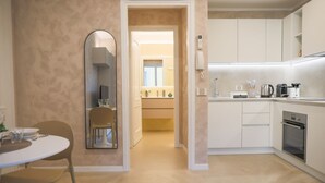 A modern kitchen with white cabinets, a built-in oven, and a countertop with a coffee maker. - BLUE WAVE by Design Studio (Bellano)