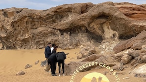 A group of people standing in a desert with rocky formations in the background. - White Desert Camp Safari (Al Bawiti)