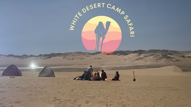A desert camp with tents and a group of people gathered around a fire. - White Desert Camp Safari (Al Bawiti)