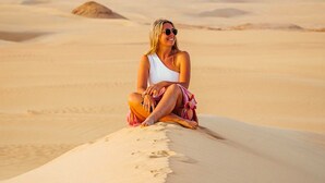 A person sitting on a sand dune in a desert landscape. - White Desert Camp Safari (Al Bawiti)