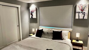 A neatly made bed with a white comforter and two pillows, a bedside table with a lamp, and a window with blinds. - ~Remodeled Mtn View Condo, Hot Tub, Modern, Fast WiFi~ (Boulder)