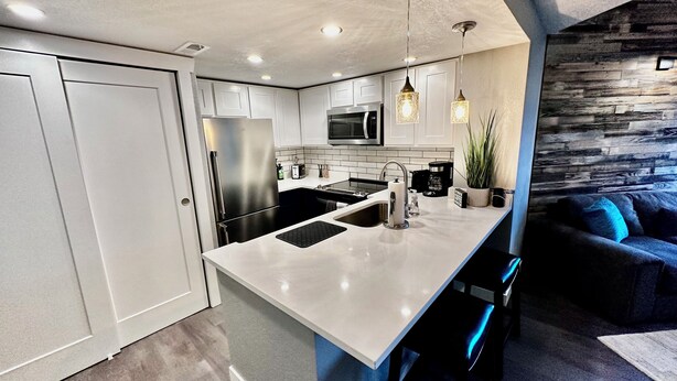 A modern kitchen with white cabinetry, stainless steel appliances, and a central island. - ~Remodeled Mtn View Condo, Hot Tub, Modern, Fast WiFi~ (Boulder)
