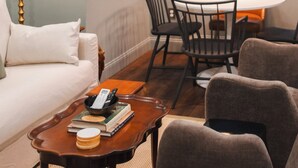 Ein modernes Wohnzimmer mit einer Couch, Sesseln, einem Couchtisch und einem Essbereich mit Tisch und Stühlen.