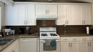 A kitchen with white cabinets, a gas stove, a dishwasher, and granite countertops. - Spacious 4-bedroom villa in charming West Covina with AC, WiFi (West Covina)