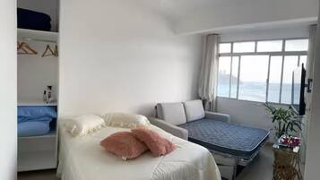 A bedroom with a bed, a sofa, a small table, and a window with a view.