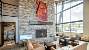 A spacious lobby with a stone wall, a fireplace, leather sofas, and large windows. - Charming Park City Loft and View at Prospector (Park City)