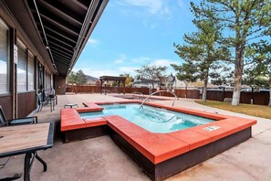 Una piscina rectangular con borde rojo, rodeada por una terraza de madera y mobiliario exterior.