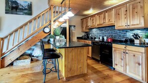 A kitchen with wooden cabinets, a black countertop, a stove, and a hanging light fixture. - Charming Park City Loft and View at Prospector (Park City)