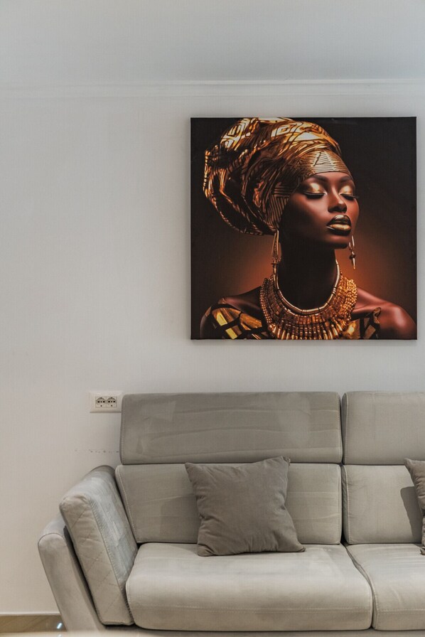 A modern living room with a grey sofa and a large framed artwork on the wall.