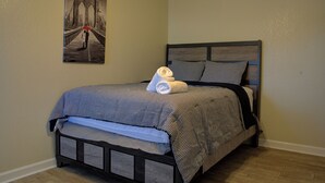 Un lit bien fait, avec une couverture à carreaux, une serviette blanche roulée et deux oreillers.