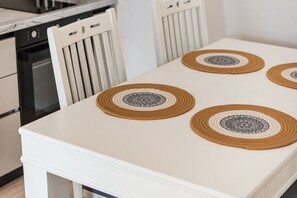 A white table with four woven placemats featuring intricate black and white designs.