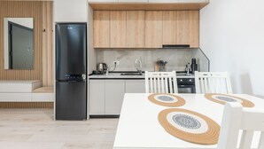 Una cocina moderna con armarios blancos, un refrigerador negro y una encimera de madera.