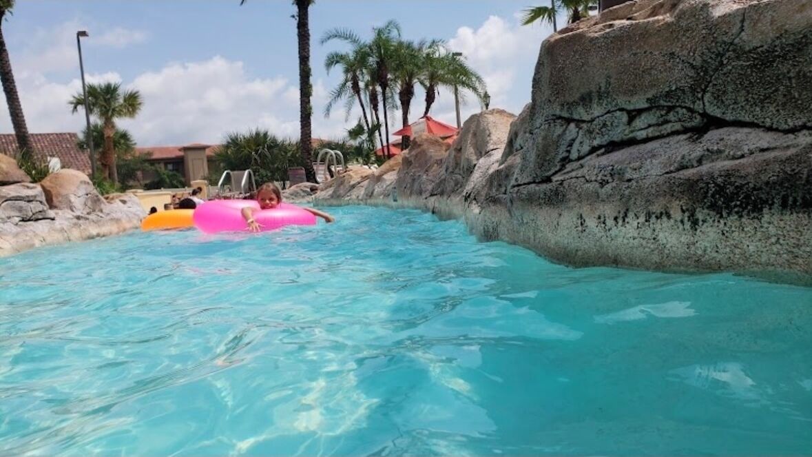 A pool area with clear water, rocks, and palm trees.