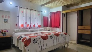 Un dormitorio con cama, cortinas, mesita de noche, lámpara y armario.