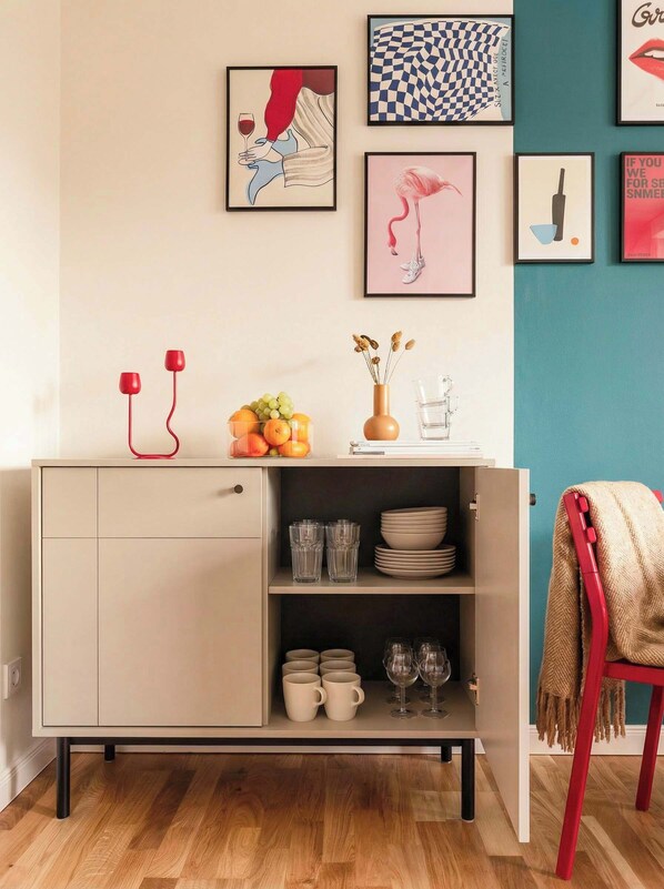 A modern kitchen with a light-colored cabinet, a fruit bowl, and a vase with dried flowers.
