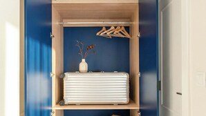 Un dressing avec une porte bleue, des étagères en bois, un radiateur et des vêtements suspendus.