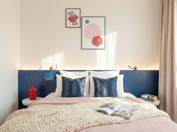 A bed with a knitted blanket, two pillows, a bedside table with a book, and wall art. - TurnKey | Wenceslas Square Two Level Apartment II (Prague)
