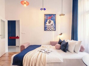 Een moderne slaapkamer met een bed, nachtlampjes, een rode plank en een lijstwerk kunstwerk aan de muur.