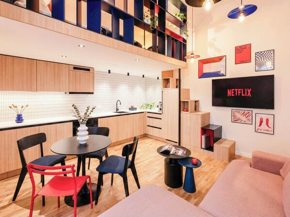A modern kitchen with a dining area, a flat-screen TV, and a bookshelf. - TurnKey | Wenceslas Square Two Level Apartment II (Prague)
