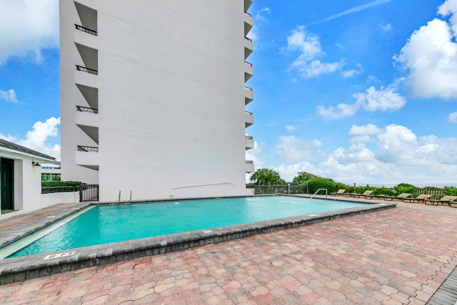 Une piscine à l’eau d’un bleu limpide, entourée d’une zone dallée avec des carreaux rouges et gris.