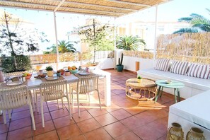 Eine Terrasse im Freien mit Esstisch, Stühlen, einer Couch und einem kleinen runden Tisch.