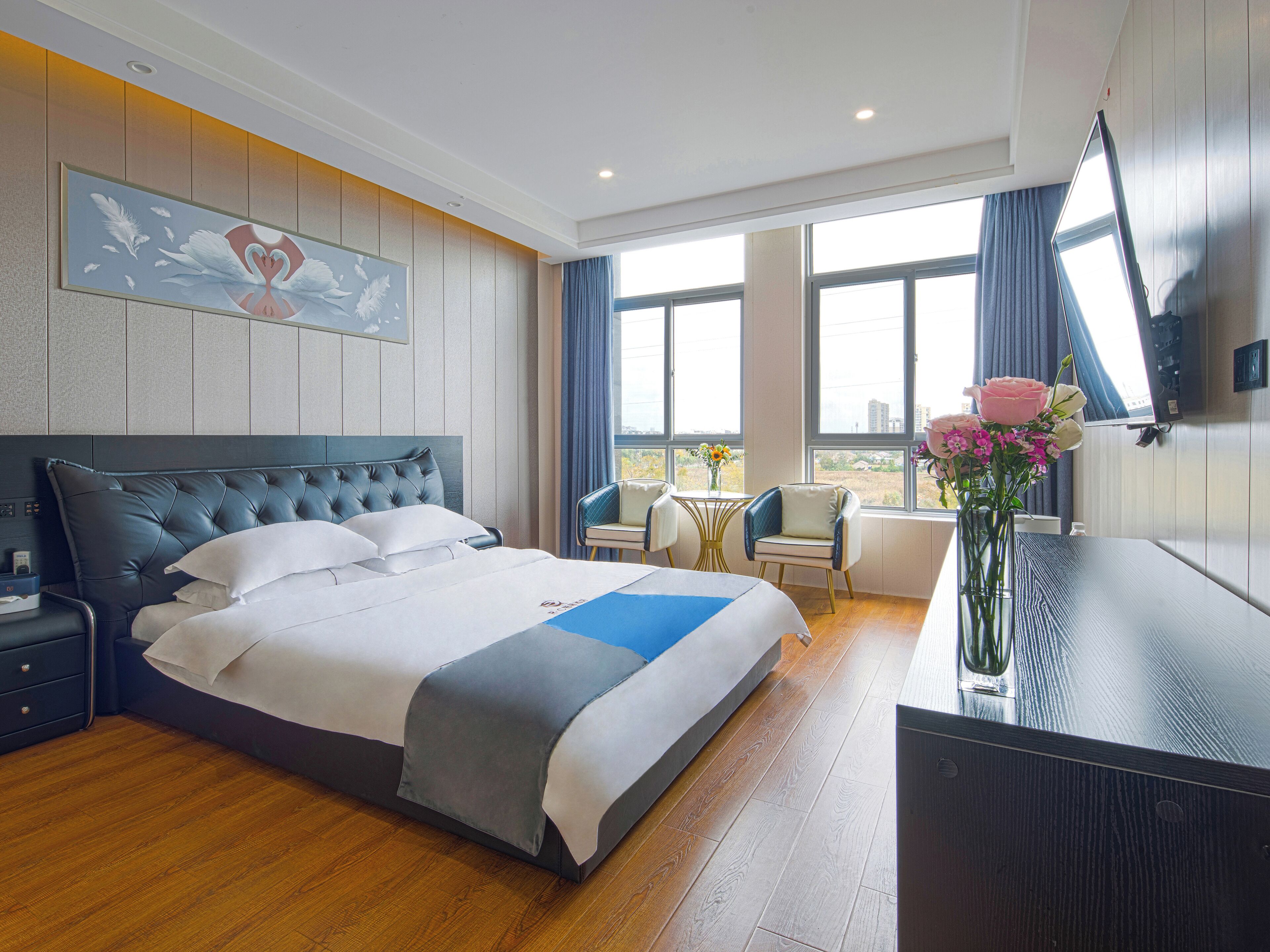 Habitación de hotel con una cama grande, un escritorio, una silla, un televisor y una ventana con vistas.
