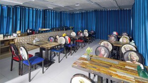A restaurant with blue curtains, wooden tables, and chairs with vintage-style plates. - RC SMART HOTEL (Yancheng)