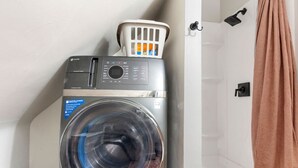Un lave-linge à chargement frontal, doté d’un panneau de commande et d’un panier à linge blanc placé sur le dessus.