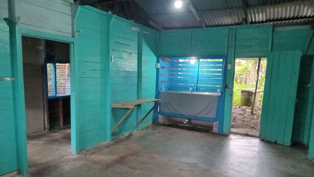 A room with teal walls, a concrete floor, and a blue door. - Se alquila casa humilde en Limón. (Limón)