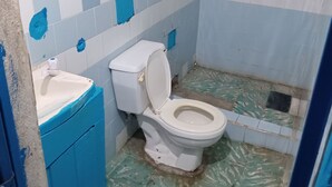 A bathroom with a toilet, sink, and blue tiles on the walls. - Se alquila casa humilde en Limón. (Limón)