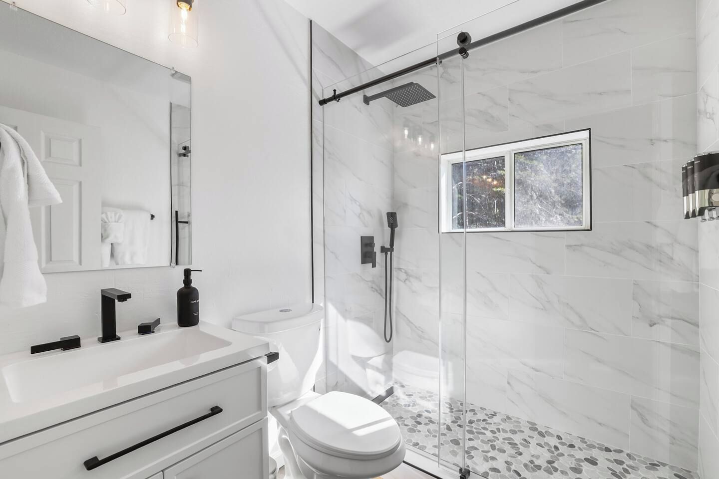 A modern bathroom with a glass-enclosed shower, a white sink, and a toilet.