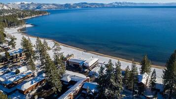 A coastal area with snow-covered buildings, a beach, and a clear view of the water.