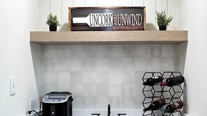 Una cocina con encimera blanca, tostadora, botellero y un cartel sobre la encimera.
