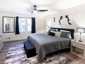 A bedroom with a bed, a bench, a nightstand, a ceiling fan, and artwork on the wall. - Modern 3-bedroom 2 bath house (Lawrenceville)