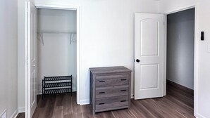 Una habitación con un armario, un mueble gris para guardar cosas y una puerta que da a otra habitación.