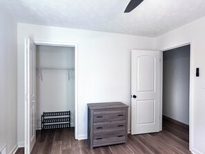 A room with a wooden floor, a gray storage unit, a white door, and a closet with a metal rack. - Modern 3-bedroom 2 bath house (Lawrenceville)