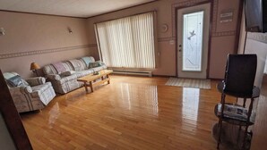 A living room with a sofa, a coffee table, a chair, and a door with a window. - Oceanfront Cottage (Charlo)