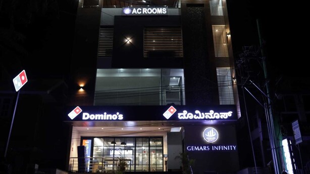 A building with signs for AC ROOMS, Domino's, and Gemars Infinity.