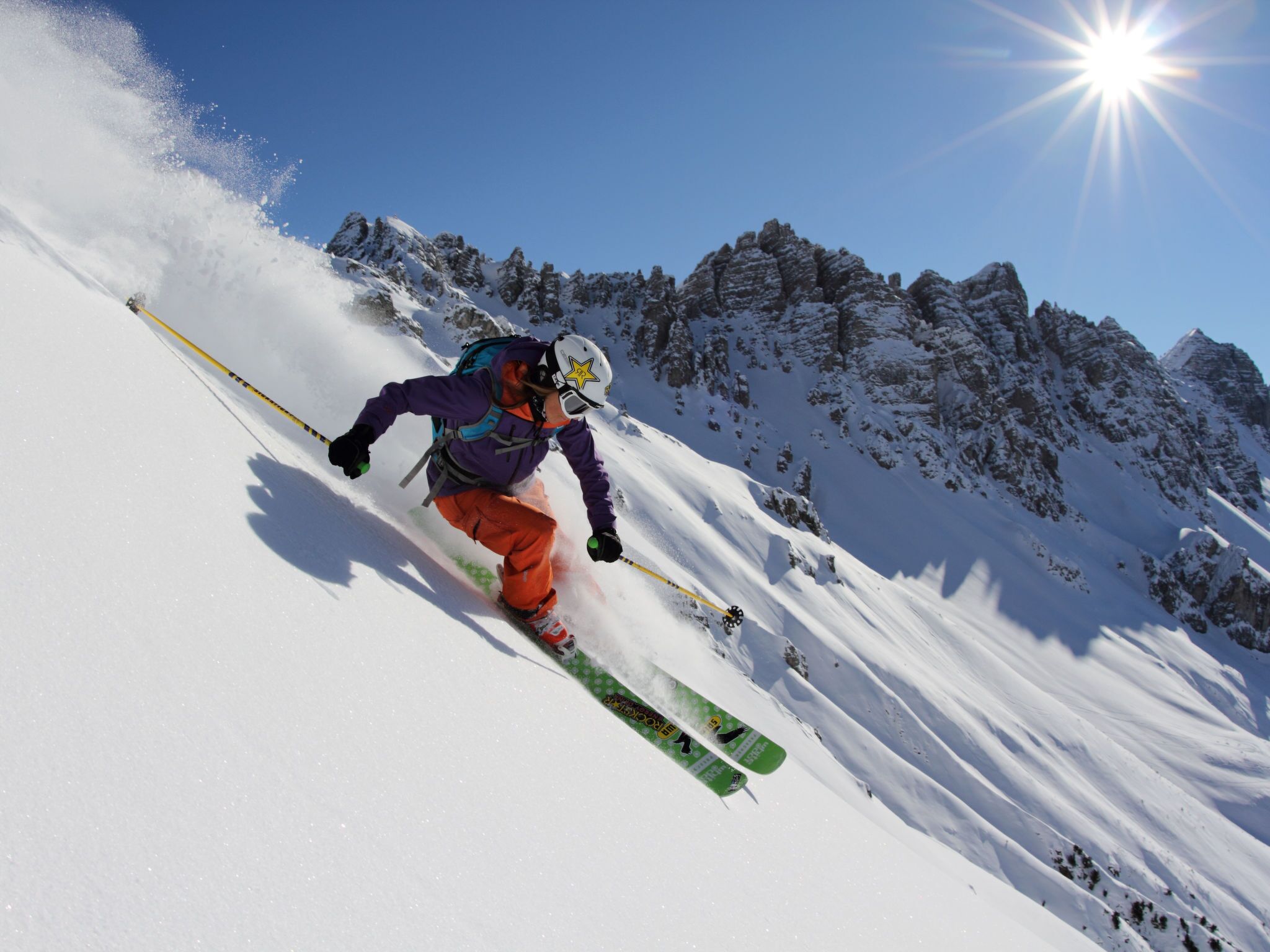 A skier on a snowy slope with a clear sky.