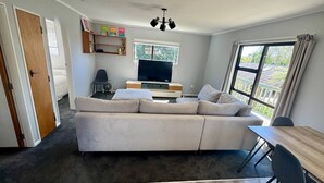 A modern living room with a grey sofa, a TV, and a dining table.