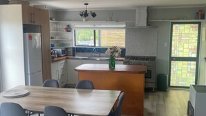 A modern kitchen with a central island, dining area with chairs, and a sofa.
